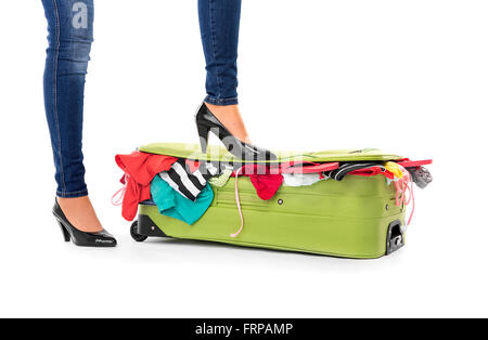 Female feet in shoes on a suitcase. White background.
