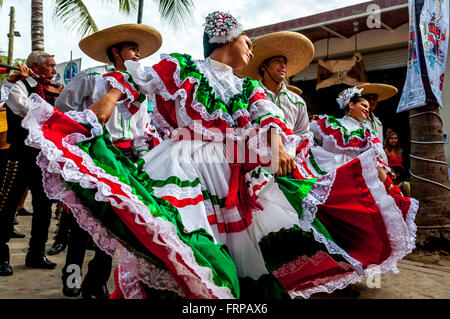 Sayulita, Nayarit: Mexican dancers wear the bright colors of Mexico's flag (red, white, green) dancing in parade with mariachis. Stock Photo