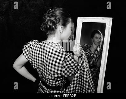 woman in a shirt looking in the mirror Stock Photo