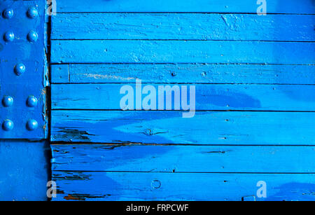 Brightly painted blue wooden background texture with weathered boards and a corner metal plate with studs Stock Photo