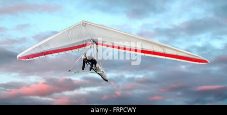Man in a harness hang-gliding at sunset against pretty pink clouds in the sky in a close up view Stock Photo