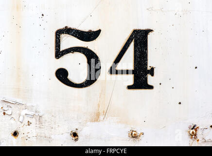 Number 54 plated on old rusty white painted surface with some missing rivets and other defects Stock Photo