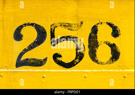 Black number 256 painted over old weathered yellow background with metal texture and rivets Stock Photo