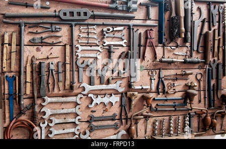 Display of various iron wrenches, drill bits, clamps and other tools on old wooden wall Stock Photo