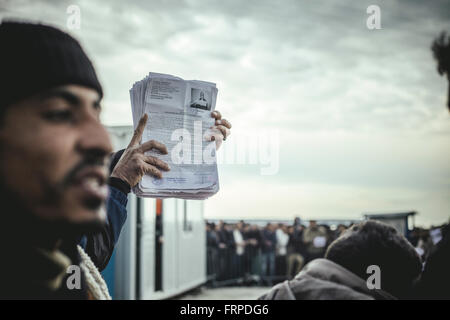 Idomeni refugee camp on the Greek Macedonia border, people queue for registration, the registration papers in the foreground Stock Photo