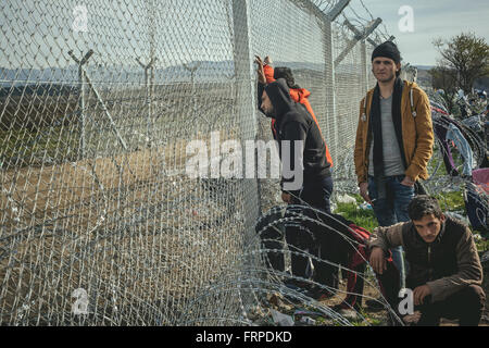 Idomeni refugee camp on the Greece Macedonia border, young men standing at the barbed wire border fence, Idomeni Stock Photo