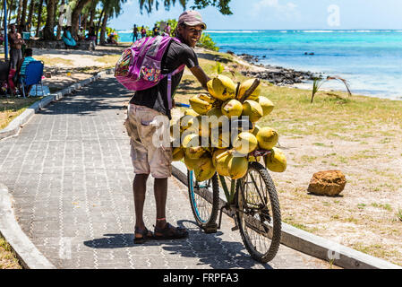 Mauritius young man selling coconuts from his bike on the beach Blue Bay, Mauritius. Stock Photo