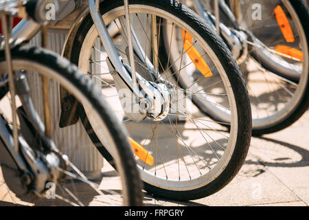 Row Of Parked Vintage Bicycles Bikes For Rent On Sidewalk. Close Up Of Wheel Stock Photo