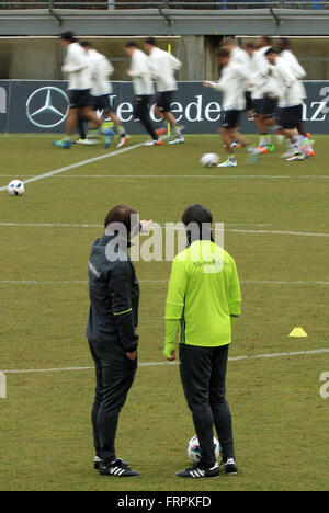 Berlin, Germany. 23rd Mar, 2016. Germany's head coach Joachim Loew (front R)and assistant coach Thomas Schneider (front L) watch their players as they warm up during a training session of the German national soccer team in Berlin, Germany, 23 March 2016. The German national soccer team is preparing for its upcoming international friendly match against England to be held in Berlin on 26 March. Photo: CHRISTIAN CHARISIUS/dpa/Alamy Live News Stock Photo
