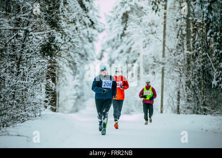 woman middle-aged athlete running down alley Park in snow. weather is cold during Chelyabinsk winter marathon Stock Photo
