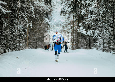 General plan winter forest and young athlete running in cold weather during Chelyabinsk winter marathon Stock Photo