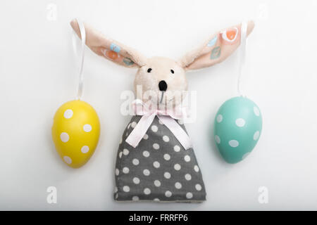 Easter Bunny toy with eggs on ears in a dress Stock Photo
