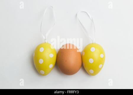 Natural brown egg and two Easter plastic artificial eggs Stock Photo