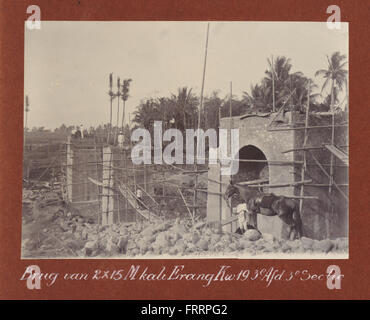 A photograph showing the construction of a railroad bridge spanning a river, built by Staatsspoorwegen (State Railway). The bridge, with a length of two 15-meter spans, is part of a larger rail infrastructure project. Stock Photo