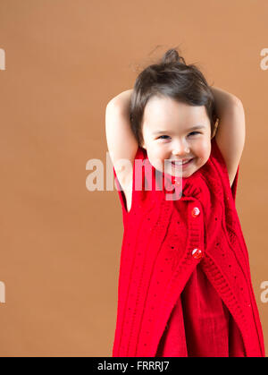 Cute little happy girl posing in a red dress Stock Photo