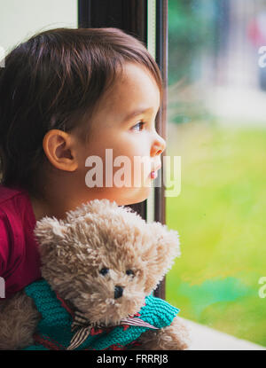 Little girl looking through window Stock Photo