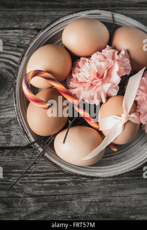 Eggs with ribbon , branches , flowers and candy on the wooden table vertical Stock Photo