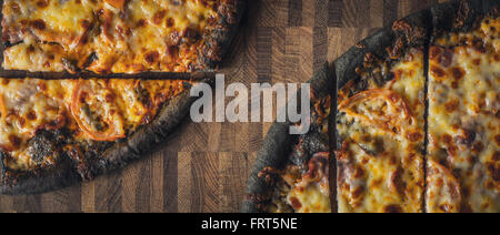 Sliced dough black pizza on the wooden table wide screen Stock Photo