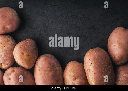 Raw potatoes on the black stone table Stock Photo