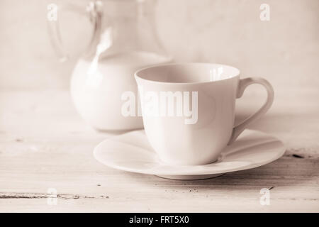 Coffee cup with  blurred jug of milk on the white table Stock Photo