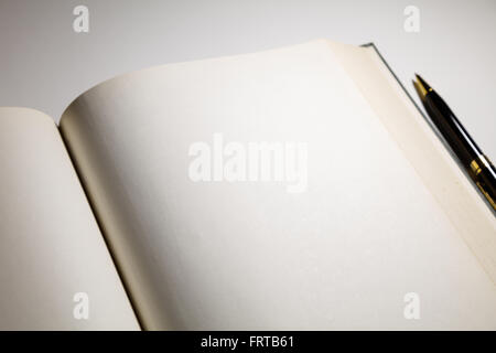Blank pages in an open book with a pen Stock Photo