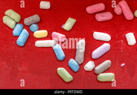 Pastel chalks in heap on red background Stock Photo