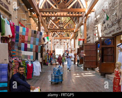 Shops and vendors in the ancient covered textile souq Bur Dubai in the old city centre of Dubai, United Arab Emirates Stock Photo