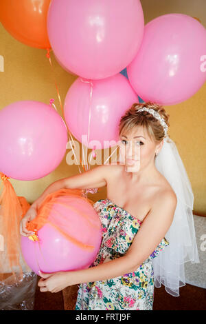 Bride in casual clothes with veil among pink balloons, preparing for wedding. Stock Photo