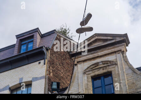 Sneakers hanging from electrical wire against a blue sky in Brussels, Belgium Stock Photo