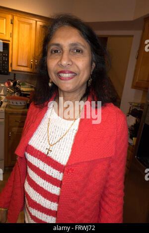 Smiling American woman from India at a Christmas party wearing a cross on a gold necklace. Mahtomedi Minnesota MN USA Stock Photo