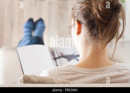 Young woman reading magazine book relaxed in sofa Stock Photo