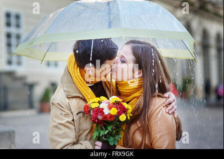 Closeup of young beautiful couple kissing under umbrella Stock Photo