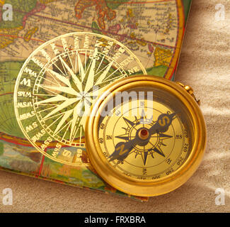 Book with retro golden compass on sand Stock Photo