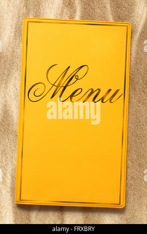 Yellow framed menu book on sand in closeup Stock Photo