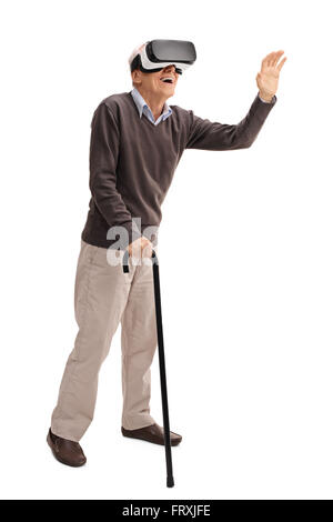 Full length portrait of a senior with a cane experiencing virtual reality through VR headset isolated on white background Stock Photo