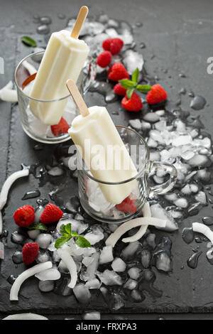 Coconut popsicles with raspberries on black background Stock Photo