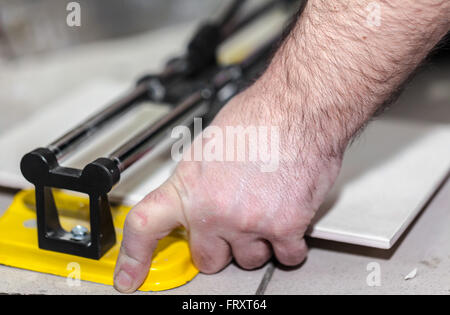Worker man cuts the ceramic tile closeup Stock Photo