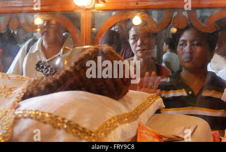 Manila, Philippines. 24th Mar, 2016. Filipino Catholics touch the image of Christ laid in a glass case at a church in Manila. On Holy Thursday, Filipinos used to visit seven to fourteen churches to reflect and pray to a series of images depicting Jesus Christ on the day of his crucifixion, and attend the evening Mass of the Lord's Supper followed by public adoration of Blessed Sacrament. Credit:  Marlo Cueto/Pacific Press/Alamy Live News Stock Photo