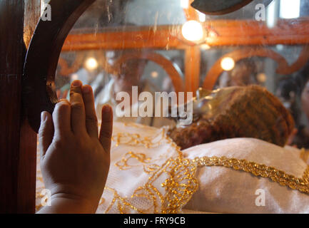 Manila, Philippines. 24th Mar, 2016. A Filipino Catholic touches the image of Christ laid in a glass case at a church in Manila. On Holy Thursday, Filipinos used to visit seven to fourteen churches to reflect and pray to a series of images depicting Jesus Christ on the day of his crucifixion, and attend the evening Mass of the Lord's Supper followed by public adoration of Blessed Sacrament. Credit:  Marlo Cueto/Pacific Press/Alamy Live News Stock Photo