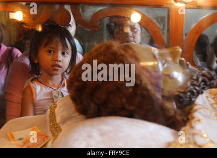 Manila, Philippines. 24th Mar, 2016. A child looks at the image of Christ laid in a glass case at a church in Manila. On Holy Thursday, Filipinos used to visit seven to fourteen churches to reflect and pray to a series of images depicting Jesus Christ on the day of his crucifixion, and attend the evening Mass of the Lord's Supper followed by public adoration of Blessed Sacrament. Credit:  Marlo Cueto/Pacific Press/Alamy Live News Stock Photo