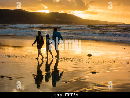 Las Palmas, Gran Canaria, Canary Islands, Spain, 24th March 2016. Weather: A family walking on the beach as the sun sets over Las Canteras beach in Las Palmas on Gran Canaria on a glorious Thurdsay in the Canary Islands; the day Prime Minister David Cameron and family arrived in the Canary Islands (Lanzarote) for their Easter holiday. Credit:  Alan Dawson News/Alamy Live News Stock Photo