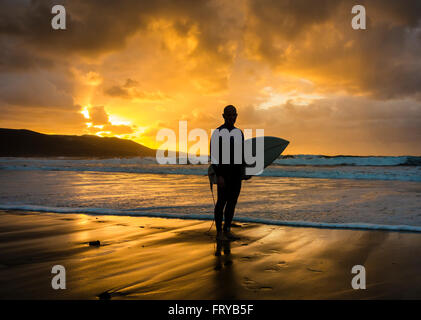 Las Palmas, Gran Canaria, Canary Islands, Spain, 24th March 2016. Weather: A surfer heading out for a late surf as the sun sets over Las Canteras beach in Las Palmas on Gran Canaria on a glorious Thurdsay in the Canary Islands; the day Prime Minister David Cameron and family arrived in the Canary Islands (Lanzarote) for their Easter holiday. Credit:  Alan Dawson News/Alamy Live News Stock Photo