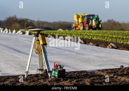 External GPS receiver being used in Burscough, Lancashire,  UK Weather.  A landscape being covered in white fleece as farmers use Trimble GPS tractor satellite guidance systems equipment to plot their fields and plant this seasons’ lettuce seedlings. Horticultural fleece is a thin, unwoven, polypropylene fabric that is used as a floating mulch to protect both early and late crops and other delicate plants from cold weather and frost, as well as insect pests during the normal growing season. Stock Photo