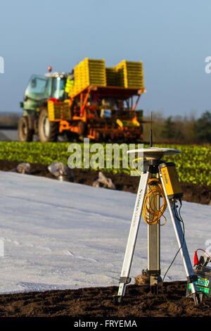 External GPS receiver used in Burscough, Lancashire, UK 25th March, 2016.  UK Weather.  A landscape being covered in white fleece as farmers use Trimble GPS tractor satellite guidance systems equipment to plot their fields and plant this seasons’ lettuce seedlings. Horticultural fleece is a thin, unwoven, polypropylene fabric that is used as a floating mulch to protect both early and late crops and other delicate plants from cold weather and frost, as well as insect pests during the normal growing season. Stock Photo