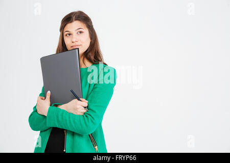 Thoughtful attractive young woman in green jacket holding folders and thinking over white background Stock Photo