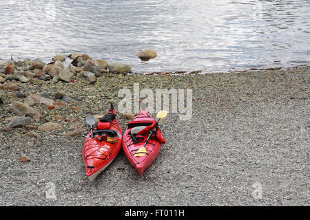 Two red kayaks on the beach in front of the water. Stock Photo
