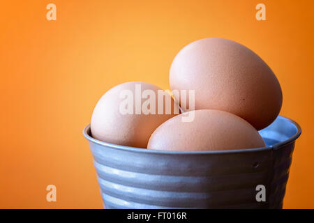 eggs in tin bucket orange background Stock Photo