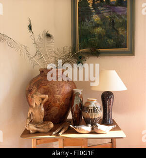 Collection of vases and a large pot with peacock feather on a small table in  nineties room Stock Photo