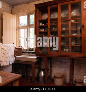 Antique Victorian glass front cupboard in Victorian style kitchen with a vintage sink Stock Photo