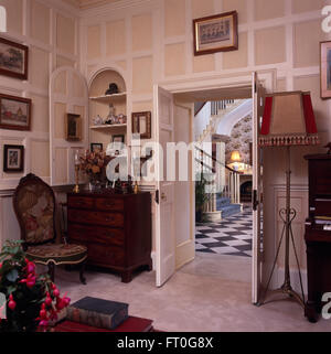 Antique tapestry chair and chest-of-drawers below alcove cupboard in painted panelled drawing room Stock Photo